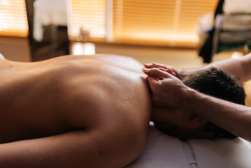 Close contact massage on a man’s neck and shoulders in a private, softly lit treatment room in Weston-super-Mare