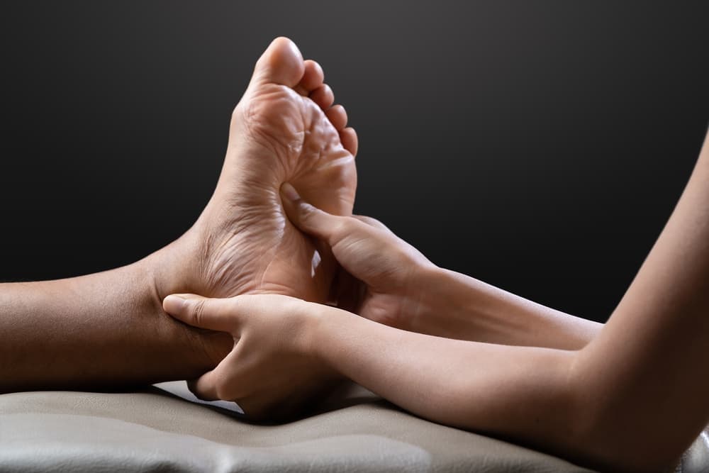 Close-up of a professional foot massage in progress, illustrating the Kaeso foot care element of a deluxe Tropic Skincare full body treatment. Perfect for promoting luxury grooming and relaxation services.