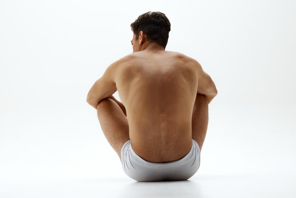 Man with smooth, hair-free back sitting in a relaxed pose after professional waxing.