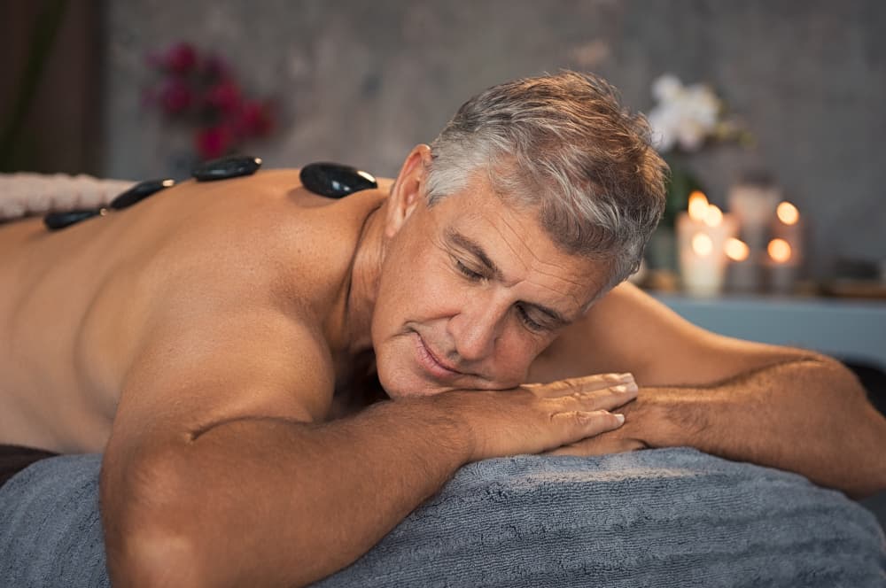 Mature man relaxing with hot stones during a professional massage session.