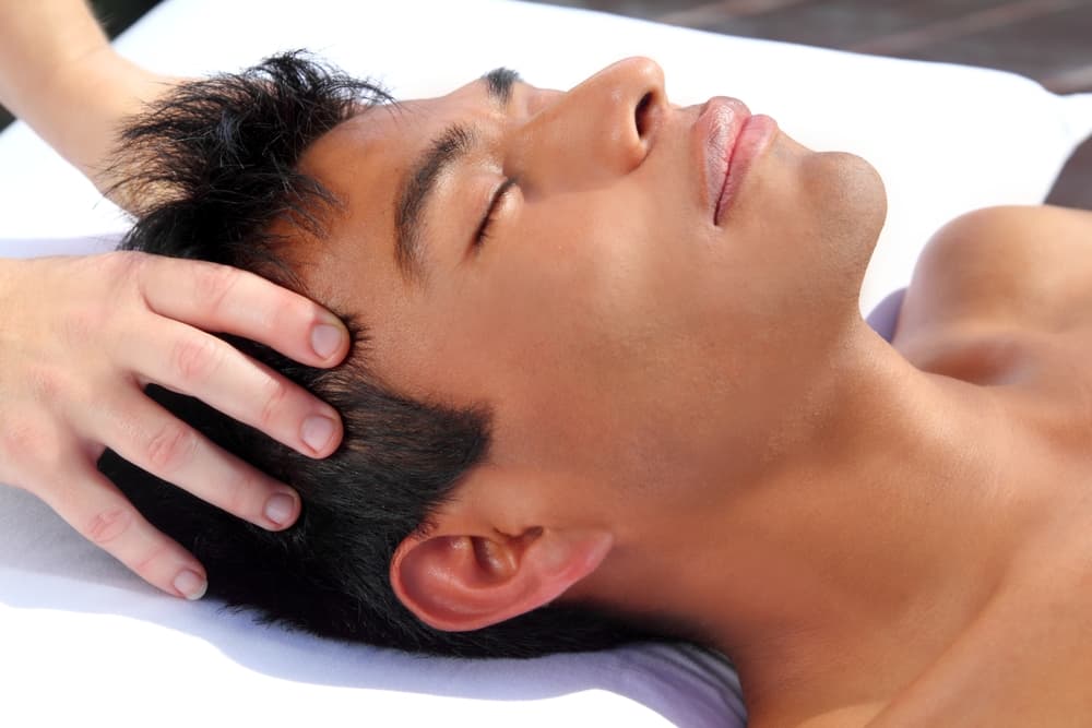 A man enjoying a relaxing Indian head massage, with a therapist applying gentle pressure to his scalp. Perfect for reducing stress and tension at Wax and Relax in Weston-super-Mare.