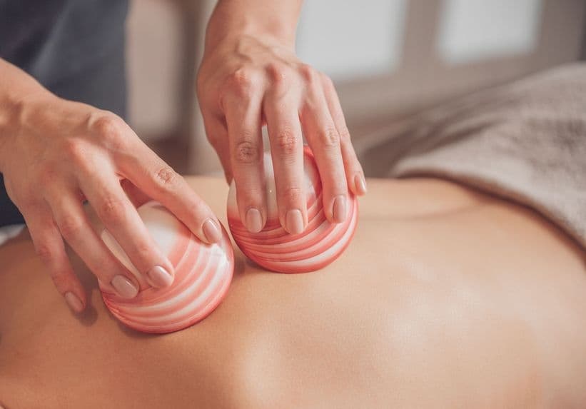 A close-up of a therapist using heated lava shells during a back massage, representing the Lava Relax full body massage with Kaeso footcare treatment.