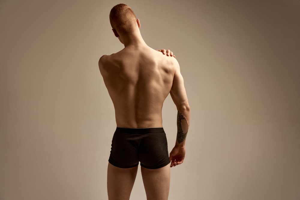 Man with smooth lower back standing confidently after waxing treatment.