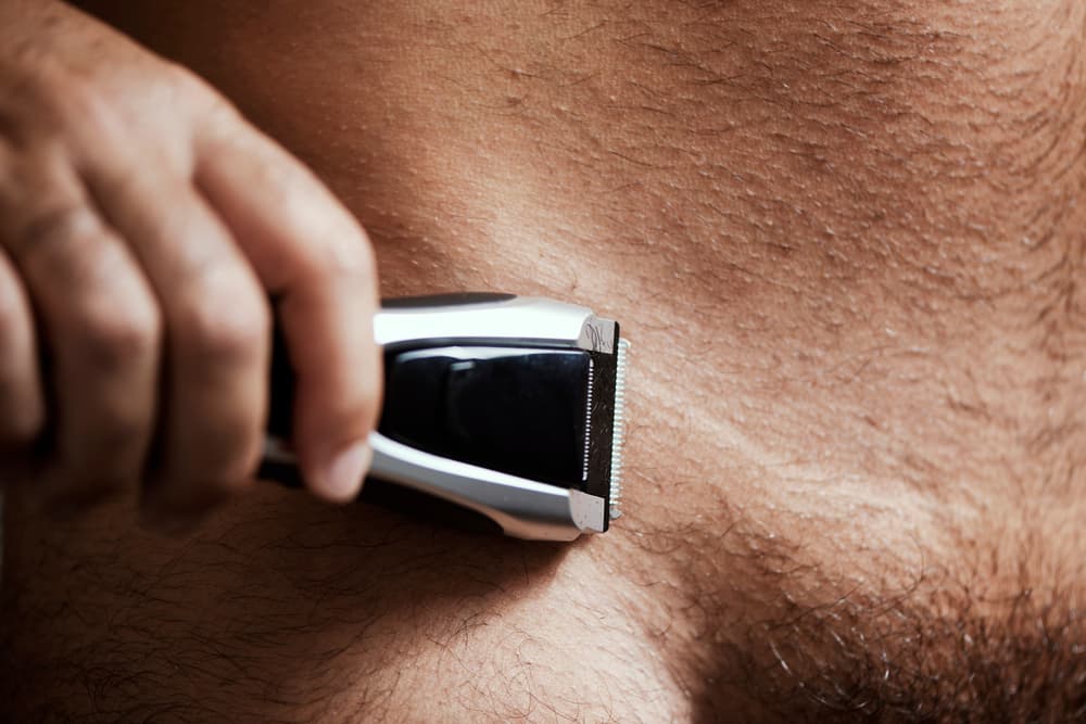 Close-up of a man using electric clippers to trim body hair as part of male grooming in Weston-super-Mare