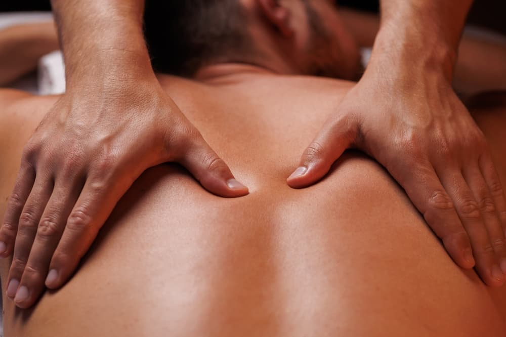 Close-up of professional back massage on a male client during a discreet naturist massage session in Weston-super-Mare