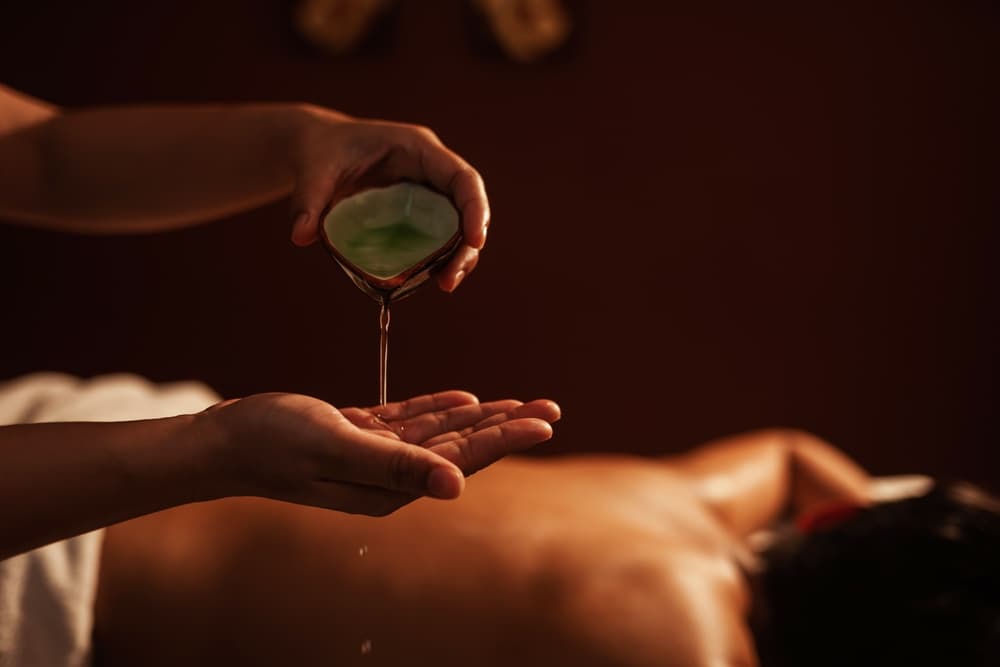 Warm massage oil being poured onto a man’s back during a 45-minute sensual massage in Weston-super-Mare