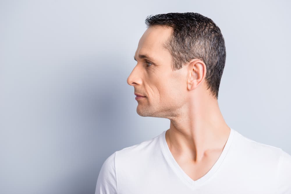 Mature man with clean neckline looking to the side after professional neck waxing treatment.