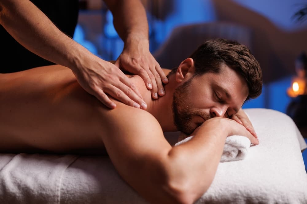 Man enjoying a relaxing back massage during a calming 60-minute session in a softly lit treatment room.