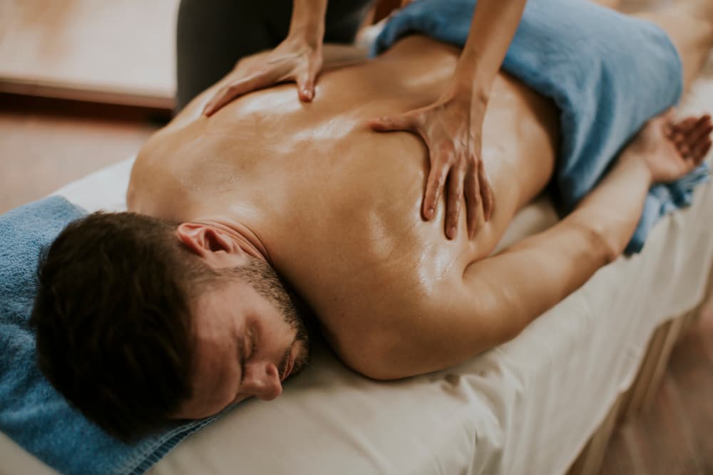 Man receiving a relaxing back massage with warm oil during a 45-minute synchronised two-therapist treatment in Weston-super-Mare